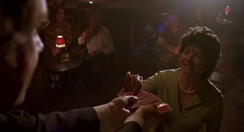 Movie still from “Breakfast on Pluto” (2005), directed by Neil Jordan – A woman holding a pair of playing cards in front of a crowd; Medium shot, Over the shoulder angle