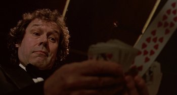 Movie still from “Breakfast on Pluto” (2005), directed by Neil Jordan – A man sitting in front of a bunch of playing cards; Close Up shot, Low angle