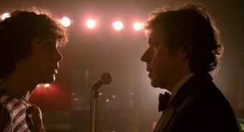 A man and a woman are standing in front of a microphone