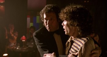 Movie still from “Breakfast on Pluto” (2005), directed by Neil Jordan – A man and a woman standing next to each other in a room; Medium shot, Over the shoulder angle