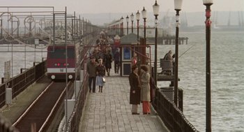 Movie still from “Breakfast on Pluto” (2005), directed by Neil Jordan – A group of people standing on a pier near a body of water; Extreme Wide shot, High angle