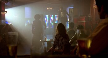 Movie still from “Breakfast on Pluto” (2005), directed by Neil Jordan – A group of people sitting in a room; Wide shot, Over the shoulder angle