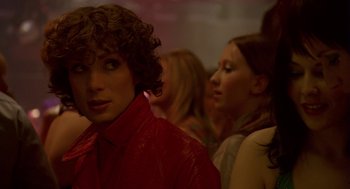 Movie still from “Breakfast on Pluto” (2005), directed by Neil Jordan – A woman in a red shirt is in a crowd of people; Close Up shot, Over the shoulder angle