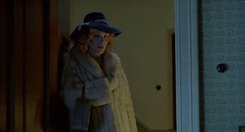 Movie still from “Breakfast on Pluto” (2005), directed by Neil Jordan – A woman in a fur coat and a hat standing next to a door; Medium shot, Over the shoulder angle