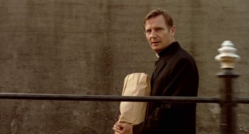 Movie still from “Breakfast on Pluto” (2005), directed by Neil Jordan – A man holding a paper bag while standing in front of a wall; Close Up shot, Low angle