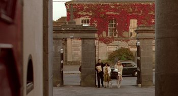 Movie still from “Breakfast on Pluto” (2005), directed by Neil Jordan – A group of people standing on the side of a road; Extreme Wide shot, Low angle