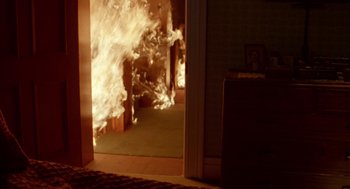 Movie still from “Breakfast on Pluto” (2005), directed by Neil Jordan – A fire is burning in the doorway of a house; Wide shot, High angle