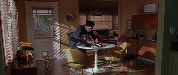 Movie still from “Breakin' All the Rules” (2004), directed by Daniel Taplitz – A man sitting at a table in a living room; Wide shot, High angle
