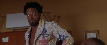 Movie still from “Breakin' All the Rules” (2004), directed by Daniel Taplitz – A man in a white shirt with colorful designs on it; Close Up shot, Low angle