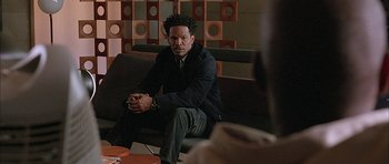 Movie still from “Breakin' All the Rules” (2004), directed by Daniel Taplitz – A man sitting on top of a couch in a living room; Medium shot, Over the shoulder angle