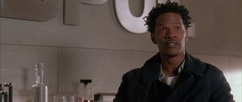 Movie still from “Breakin' All the Rules” (2004), directed by Daniel Taplitz – A man in a black jacket sitting in front of a white sign; Close Up shot, Over the shoulder angle