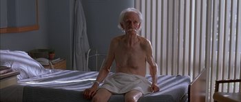 Movie still from “Breakin' All the Rules” (2004), directed by Daniel Taplitz – An older man sitting on a bed with a towel around his waist; Medium shot, High angle