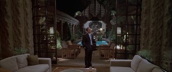 Movie still from “Breakin' All the Rules” (2004), directed by Daniel Taplitz – A man in a suit standing in front of a pool at night; Wide shot, Over the shoulder angle