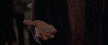 Movie still from “Breakin' All the Rules” (2004), directed by Daniel Taplitz – A person holding a coin in their hand; Extreme Close Up shot, High angle