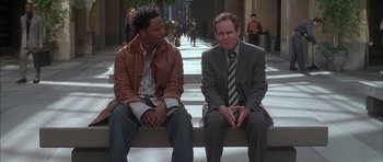 Movie still from “Breakin' All the Rules” (2004), directed by Daniel Taplitz – Two men sitting on a bench in the middle of the street; Medium shot, High angle