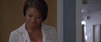 Movie still from “Breakin' All the Rules” (2004), directed by Daniel Taplitz – A woman wearing a white lab coat and pink shirt; Close Up shot, Over the shoulder angle