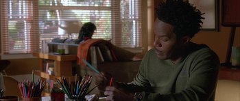 Movie still from “Breakin' All the Rules” (2004), directed by Daniel Taplitz – A man sitting at a table with a bunch of colored pencils; Close Up shot, Over the shoulder angle