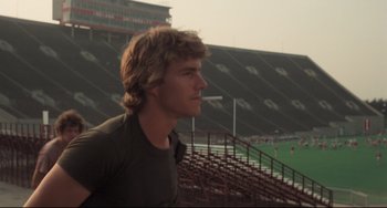 Movie still from “Breaking Away” (1979), directed by Peter Yates – A man standing in front of bleachers in a stadium; Close Up shot, Low angle