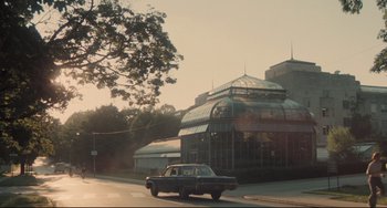 Movie still from “Breaking Away” (1979), directed by Peter Yates – A car is driving down the street near a building; Extreme Wide shot, Low angle