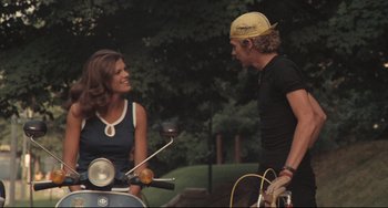 Movie still from “Breaking Away” (1979), directed by Peter Yates – A man and a woman talking to each other on a moped; Medium shot, Low angle