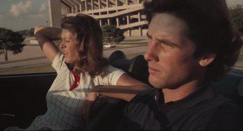 Movie still from “Breaking Away” (1979), directed by Peter Yates – A man and a woman sitting in the back of a car; Medium shot, Low angle