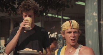 Movie still from “Breaking Away” (1979), directed by Peter Yates – Two young men standing next to each other on a street; Medium shot, Low angle