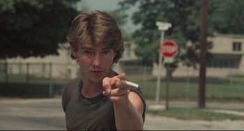 Movie still from “Breaking Away” (1979), directed by Peter Yates – A young man holding a cigarette in his hand; Close Up shot, Over the shoulder angle