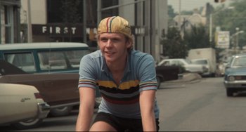 Movie still from “Breaking Away” (1979), directed by Peter Yates – A man riding a bicycle down a street; Close Up shot, Low angle