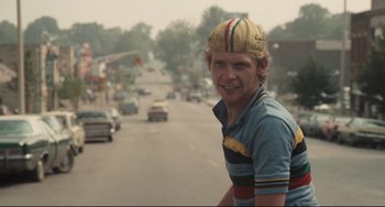 Movie still from “Breaking Away” (1979), directed by Peter Yates – A man wearing a helmet on the side of the road; Close Up shot, Over the shoulder angle