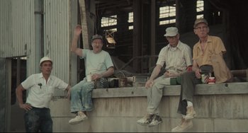 Movie still from “Breaking Away” (1979), directed by Peter Yates – A group of men sitting on a cement wall; Wide shot, Low angle