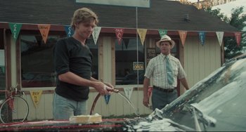 Movie still from “Breaking Away” (1979), directed by Peter Yates – Two men standing in front of an open grill; Medium shot, Over the shoulder angle