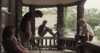 Movie still from “Breaking Away” (1979), directed by Peter Yates – A man sitting on top of a bench next to a bicycle; Wide shot, Low angle