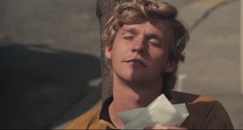 Movie still from “Breaking Away” (1979), directed by Peter Yates – A young man holding a piece of paper while standing next to a tree; Close Up shot, Low angle