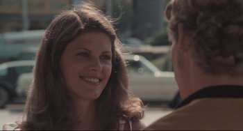Movie still from “Breaking Away” (1979), directed by Peter Yates – A young woman smiles while talking to an older man; Close Up shot, Over the shoulder angle