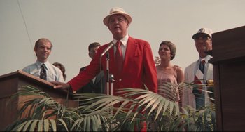 Movie still from “Breaking Away” (1979), directed by Peter Yates – A man in a red suit and a hat is speaking; Medium shot, Low angle