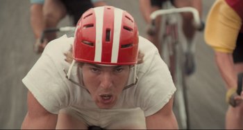 Movie still from “Breaking Away” (1979), directed by Peter Yates – A man wearing a red and white helmet on a bicycle; Close Up shot, Low angle