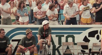 Movie still from “Breaking Away” (1979), directed by Peter Yates – A man riding a bike in front of a group of people; Wide shot, Low angle
