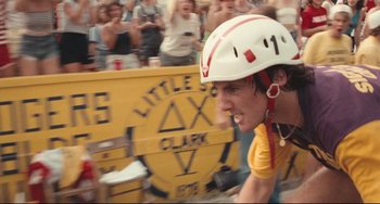 Movie still from “Breaking Away” (1979), directed by Peter Yates – A man riding a bike down a street next to a crowd of onlookers; Close Up shot, Low angle