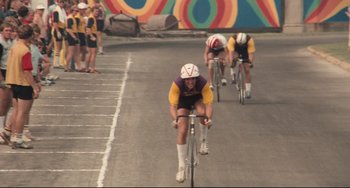 Movie still from “Breaking Away” (1979), directed by Peter Yates – A group of men riding bikes down a street; Extreme Wide shot, Low angle