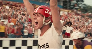 Movie still from “Breaking Away” (1979), directed by Peter Yates – A man in a helmet is raising his hands in the air; Close Up shot, Low angle