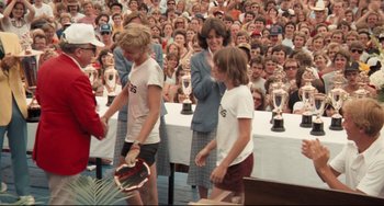 Movie still from “Breaking Away” (1979), directed by Peter Yates – A group of people standing in front of an audience holding tennis rackets; Medium shot, High angle