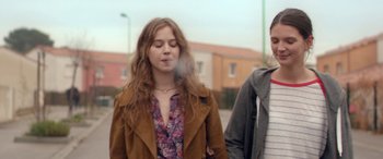 Movie still from “Breathe” (2014), directed by Mélanie Laurent – A young woman is smoking a cigarette while standing next to a young man; Medium shot, Over the shoulder angle