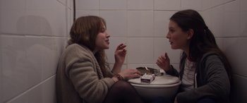 Movie still from “Breathe” (2014), directed by Mélanie Laurent – Two women sitting on a toilet in a bathroom; Medium shot, Over the shoulder angle
