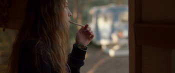 Movie still from “Breathe” (2014), directed by Mélanie Laurent – A woman is smoking a cigarette on the side of the road; Medium shot, Over the shoulder angle