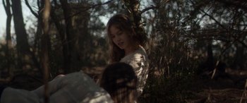 Movie still from “Breathe” (2014), directed by Mélanie Laurent – A young woman in a white shirt is in the woods; Medium shot, Over the shoulder angle