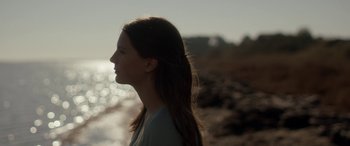 Movie still from “Breathe” (2014), directed by Mélanie Laurent – A woman with long brown hair standing on the beach; Close Up shot, Over the shoulder angle