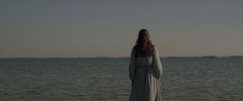 Movie still from “Breathe” (2014), directed by Mélanie Laurent – A woman standing on a beach looking out at the ocean; Medium shot, Over the shoulder angle