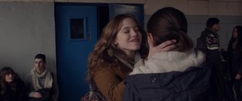 Movie still from “Breathe” (2014), directed by Mélanie Laurent – A woman is hugging another woman in front of a blue door; Close Up shot, Over the shoulder angle