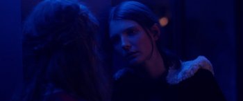 Movie still from “Breathe” (2014), directed by Mélanie Laurent – A woman with long dark hair standing next to another woman in a dark room; Close Up shot, Over the shoulder angle
