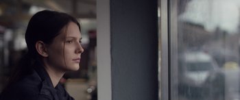 Movie still from “Breathe” (2014), directed by Mélanie Laurent – A woman looking out of a window at a building; Close Up shot, Over the shoulder angle
